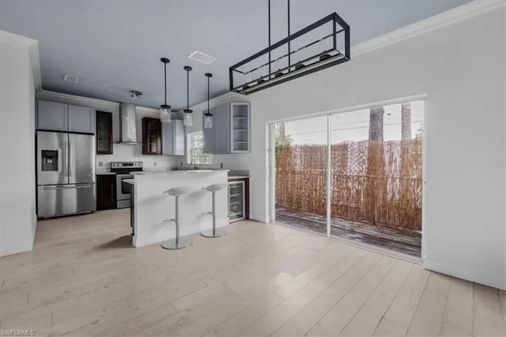 Kitchen featuring a kitchen island, stainless steel appliances, light wood-type flooring, and ornamental molding