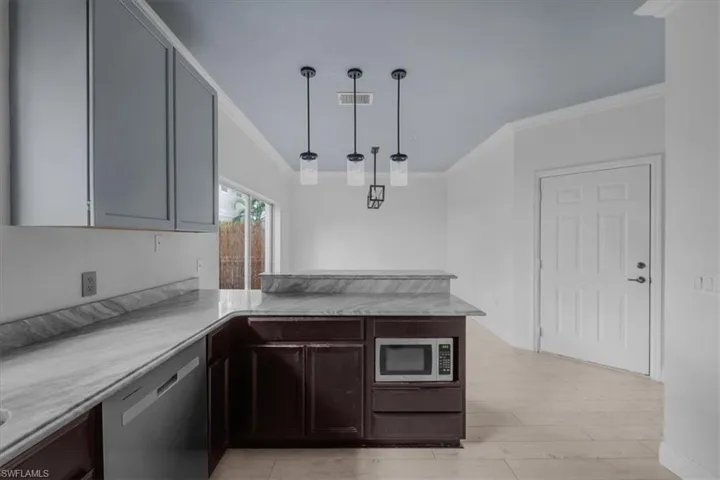 Kitchen featuring kitchen peninsula, crown molding, decorative light fixtures, and appliances with stainless steel finishes