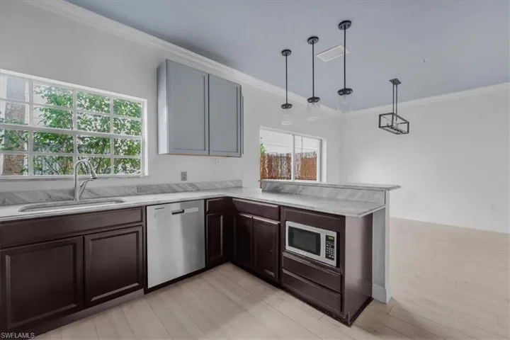 Kitchen with light wood-type flooring, stainless steel appliances, a healthy amount of sunlight, and sink