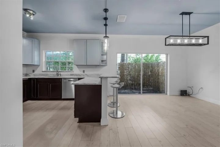 Kitchen featuring dishwasher, a kitchen breakfast bar, light hardwood / wood-style flooring, and light stone countertops
