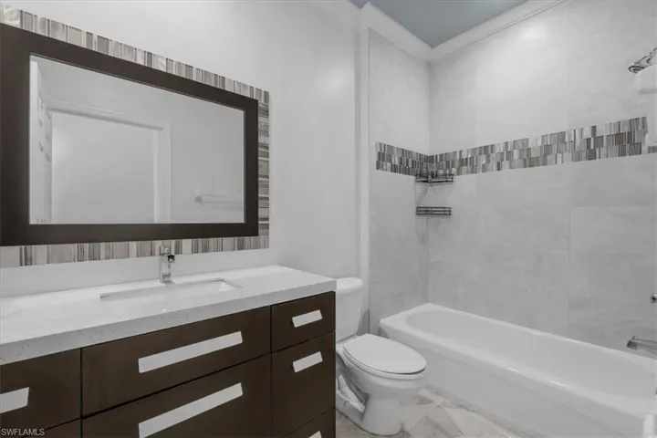 Full bathroom featuring tiled shower / bath combo, toilet, crown molding, and vanity