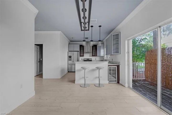 Kitchen featuring hanging light fixtures, beverage cooler, stainless steel appliances, light hardwood / wood-style flooring, and a breakfast bar