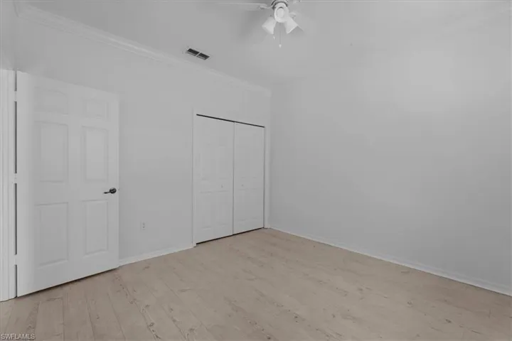 bedroom with ceiling fan, a closet, crown molding, and light hardwood / wood-style flooring
