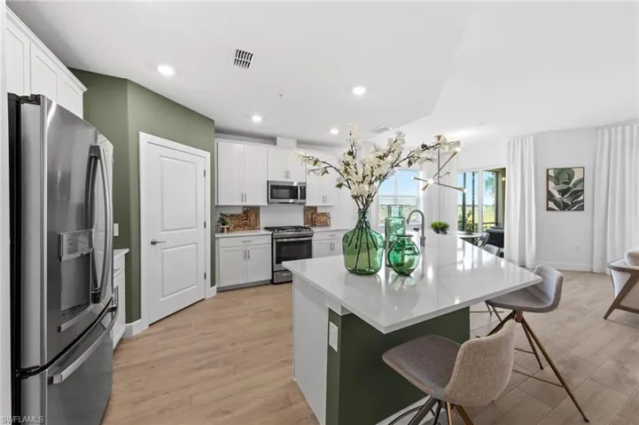 Modern kitchen featuring white cabinetry, stainless steel appliances, a center island with a white countertop, wood-finish flooring, and recessed lighting