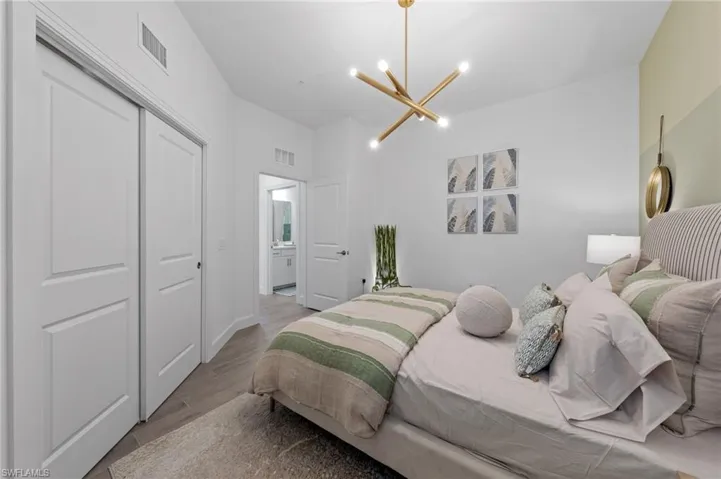 Wood-finish flooring, built-in closet with sliding doors, contemporary ceiling light fixture, and a solid core door