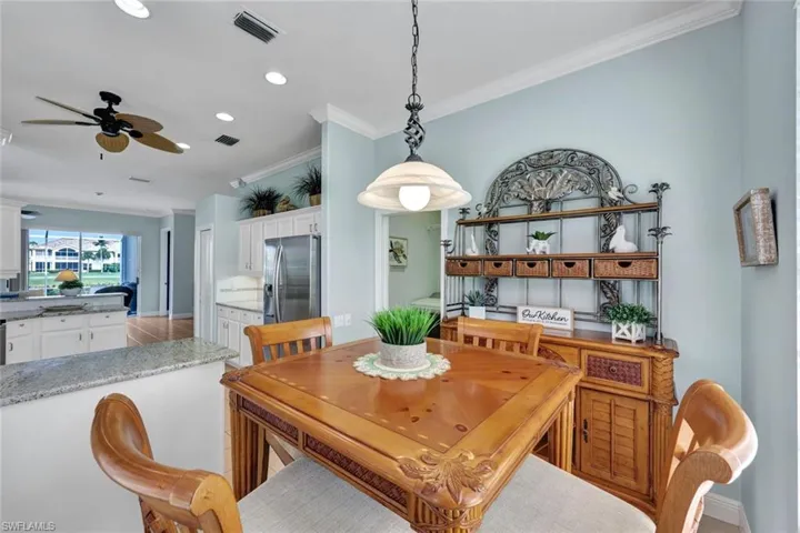 Tiled dining room with ceiling fan and crown molding