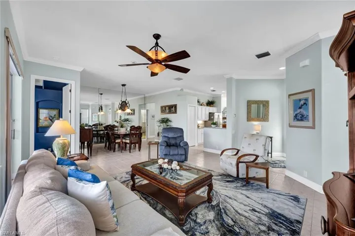 Tiled living room with ceiling fan and crown molding