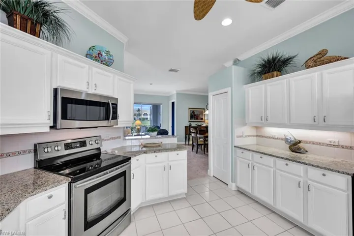 Kitchen with crown molding, appliances with stainless steel finishes, white cabinets, tasteful backsplash, and ceiling fan