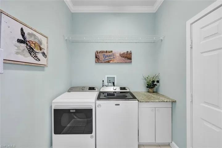 Clothes washing area with cabinets, ornamental molding, washer and clothes dryer, and washer hookup