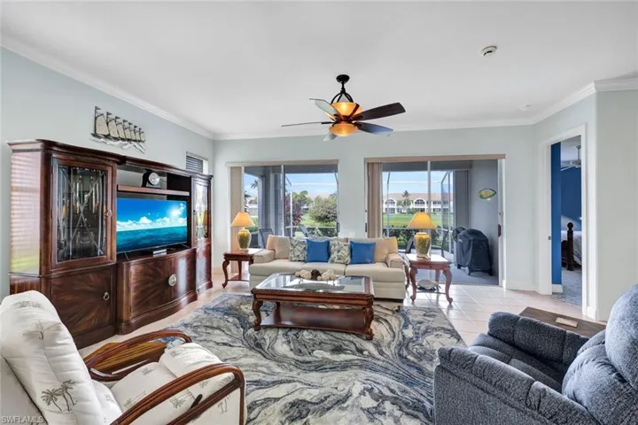 Tiled living room featuring ceiling fan and crown molding