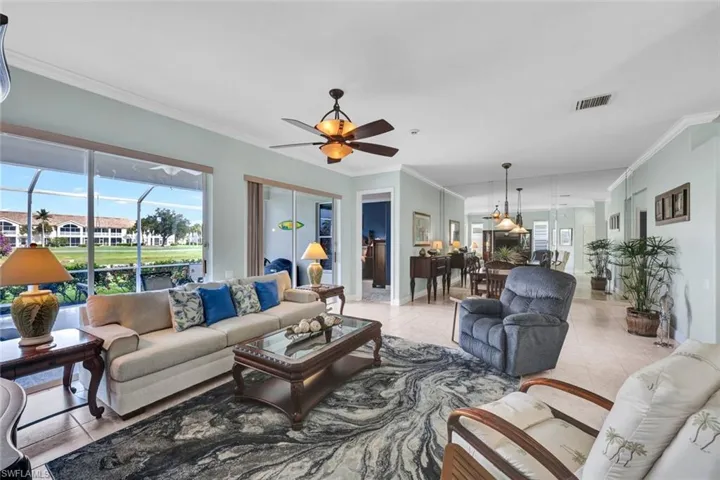 Tiled living room with ceiling fan and crown molding