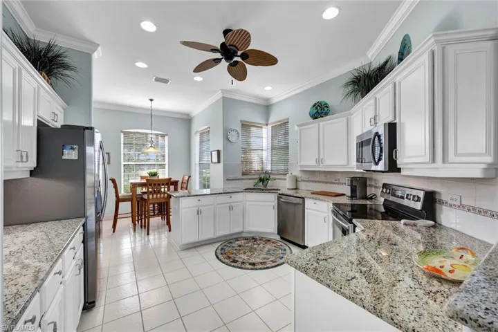 Kitchen featuring ceiling fan, kitchen peninsula, stainless steel appliances, backsplash, and white cabinets