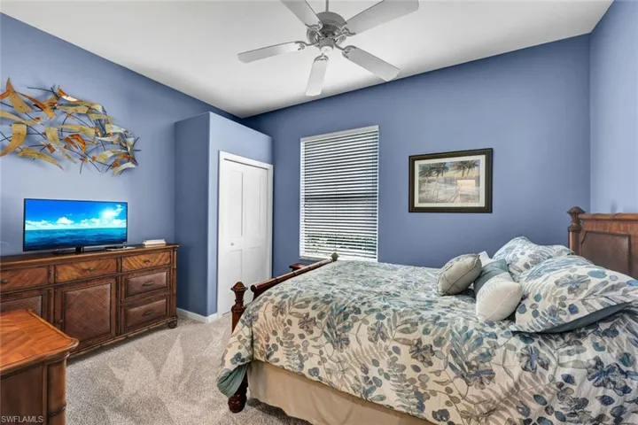 Bedroom with ceiling fan, a closet, and light colored carpet