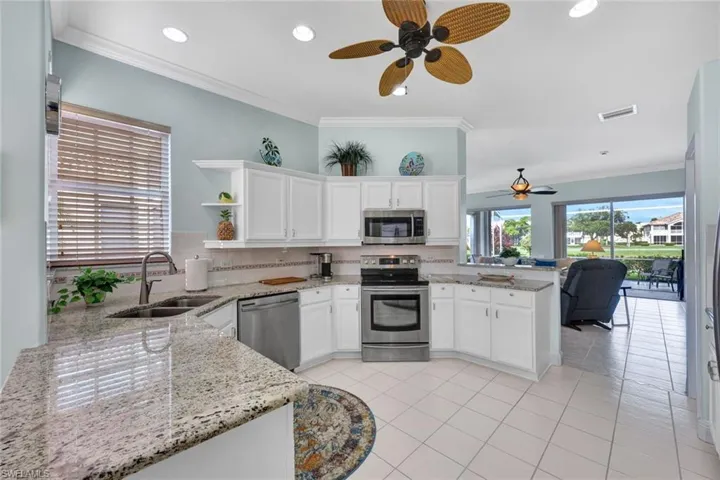 Kitchen with stainless steel appliances, kitchen peninsula, sink, ceiling fan, and light tile floors