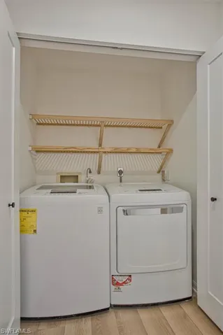 Laundry area featuring light wood finished floors and separate washer and dryer