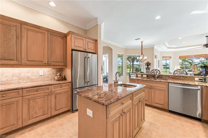 Kitchen with ornamental molding, a kitchen island with sink, stainless steel appliances, and sink