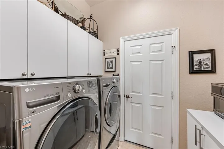 Washroom featuring washing machine and dryer and cabinets