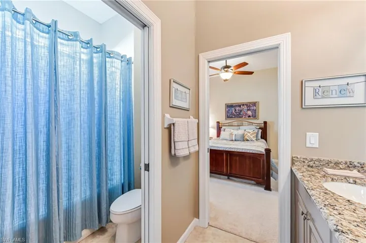 Bathroom with toilet, ceiling fan, tile patterned floors, a shower with curtain, and vanity
