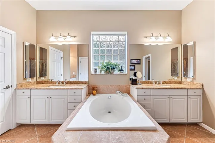 Bathroom featuring vanity, a relaxing tiled tub, and tile patterned flooring