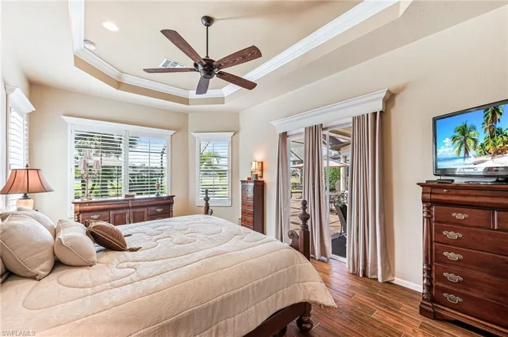 Bedroom featuring access to outside, a tray ceiling, ceiling fan, ornamental molding, and dark hardwood / wood-style floors