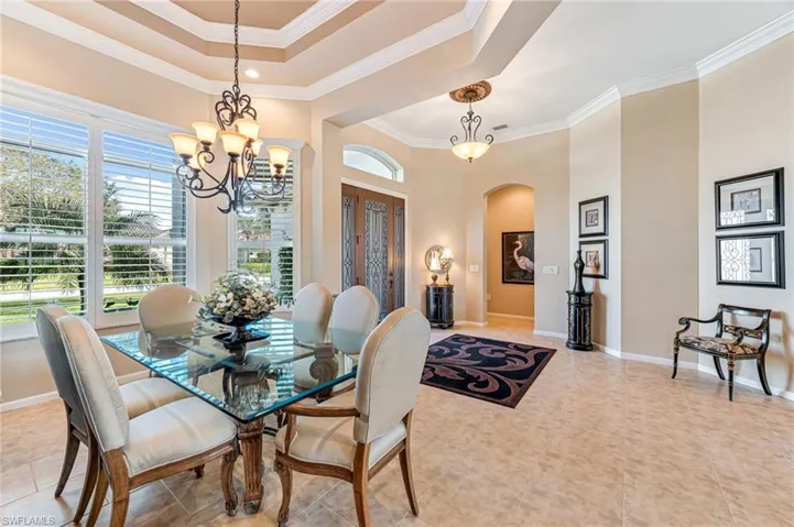 Dining area featuring crown molding, a notable chandelier, tile patterned floors, and a raised ceiling