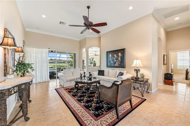 Tiled living room with crown molding, a healthy amount of sunlight, and ceiling fan