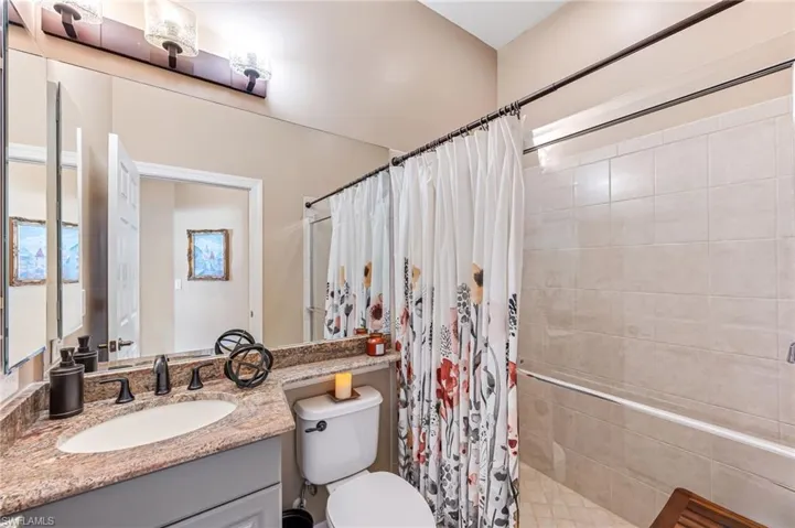 Bathroom with vanity, a shower with curtain, and toilet