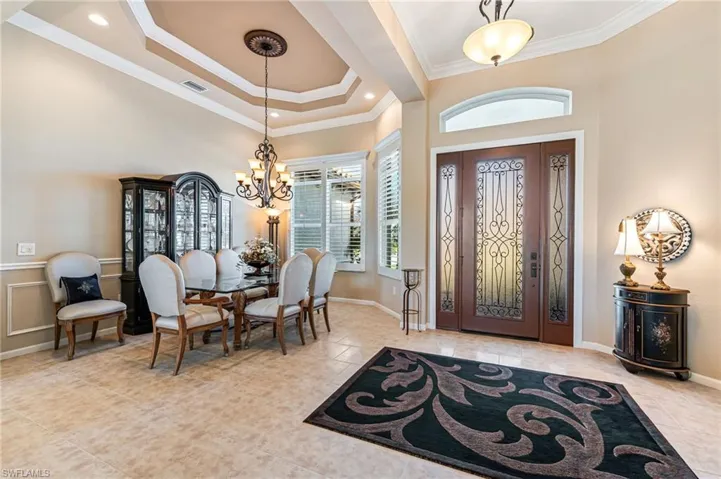 Foyer entrance with crown molding, a notable chandelier, and light tile patterned floors