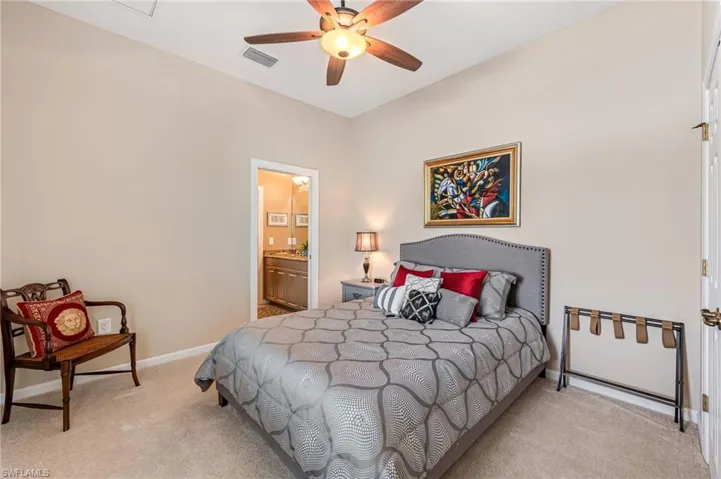 Carpeted bedroom featuring connected bathroom and ceiling fan