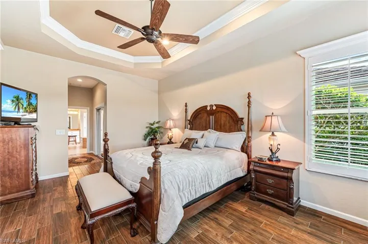 Bedroom featuring ceiling fan, crown molding, dark hardwood / wood-style flooring, and a raised ceiling