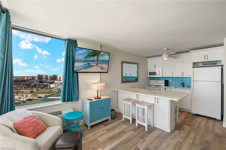 Kitchen featuring white cabinets, white appliances, a breakfast bar area, and light hardwood / wood-style flooring