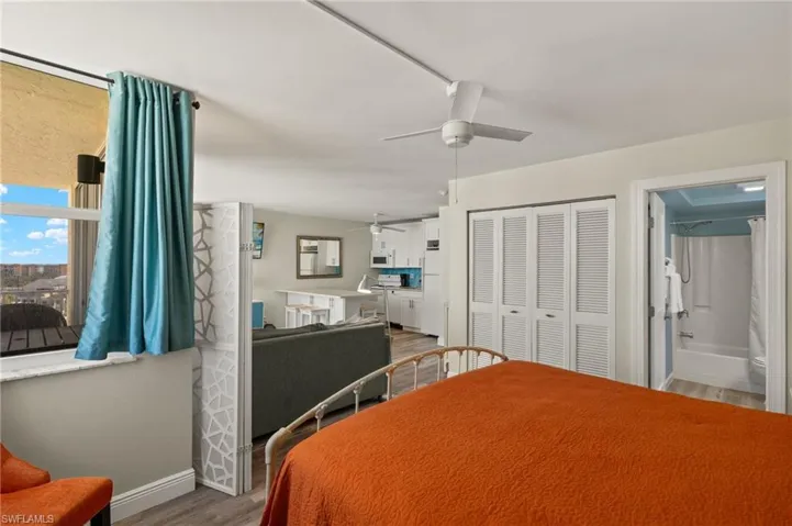 Bedroom with a closet, ensuite bath, ceiling fan, and wood-type flooring