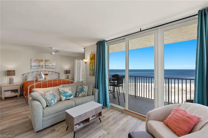 Bedroom featuring floor to ceiling windows, a view of the beach, a water view, light wood-type flooring, and access to outside
