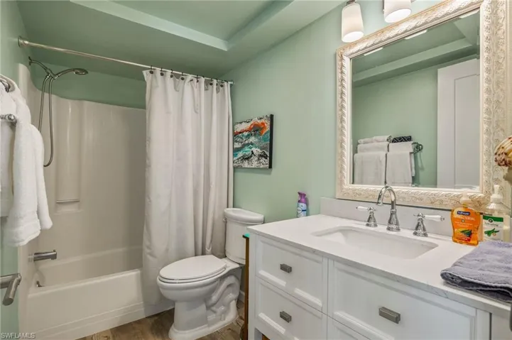 Full bathroom with hardwood / wood-style flooring, vanity, toilet, and shower / bath combo
