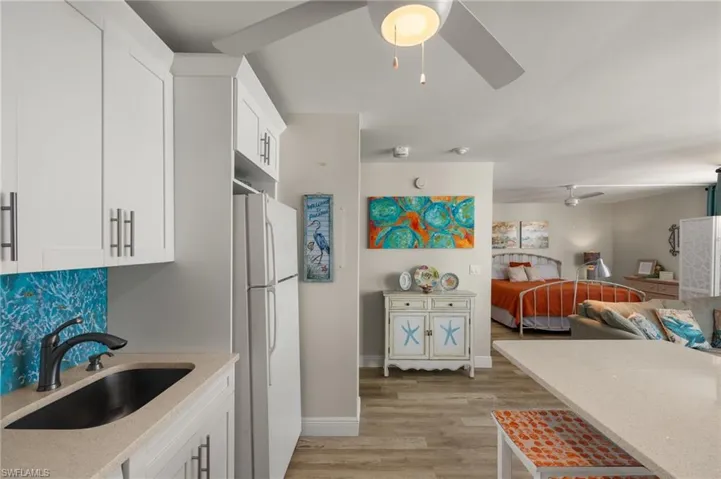 Kitchen with white cabinets, ceiling fan, white refrigerator, and sink