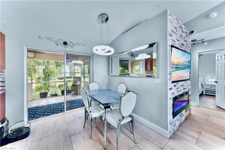 Dining area featuring vaulted ceiling, a fireplace, wood finish floors, and a chandelier