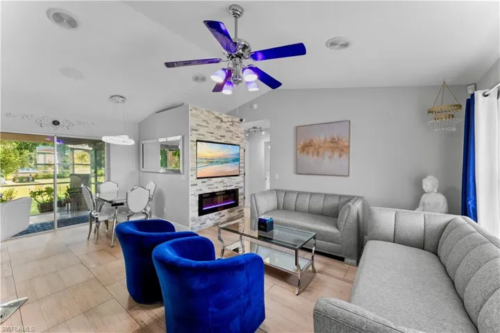 Living room with lofted ceiling, ceiling fan, and a fireplace