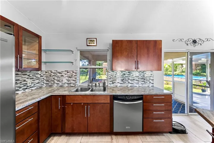 Kitchen featuring stainless steel appliances, backsplash, light stone counters, and open shelves