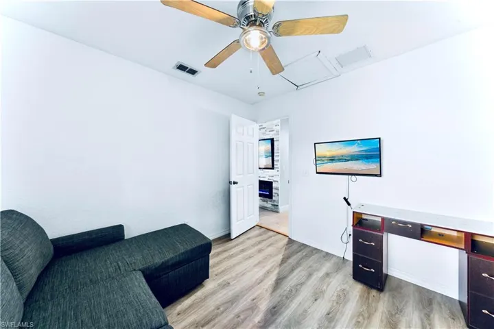 Home office featuring light wood-type flooring, ceiling fan, and attic access