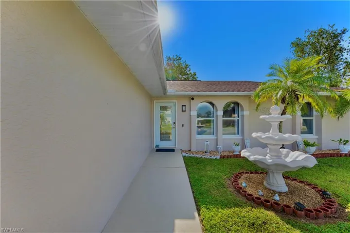 Entrance to property featuring stucco siding, a yard, and a shingled roof