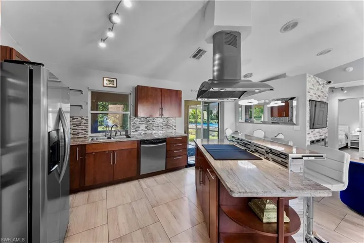 Kitchen featuring appliances with stainless steel finishes, backsplash, open shelves, vaulted ceiling, and island exhaust hood
