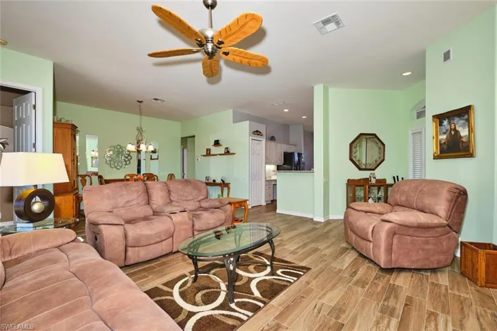 Living room featuring wood finish floors, ceiling fan, and suspended lighting