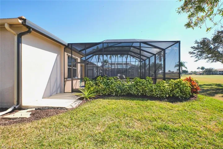 View of grassy yard featuring glass enclosure and a sunroom