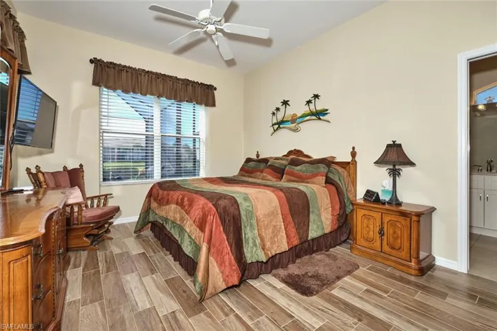 Bedroom featuring wood tiled floors, a ceiling fan, and ensuite bathroom