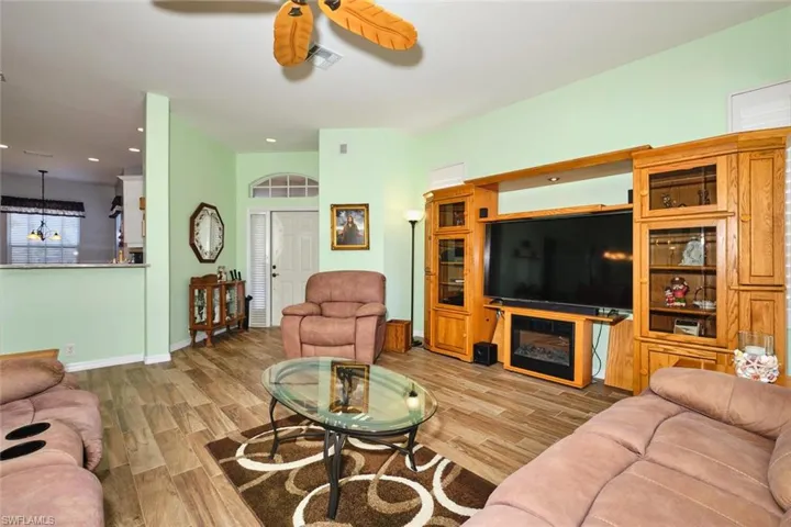 Living room with light wood finished floors, ceiling fan, and recessed lighting