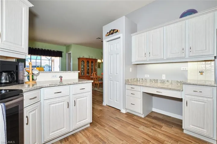 Kitchen with light stone counters, white cabinetry, electric range, wood finish floors, and decorative backsplash