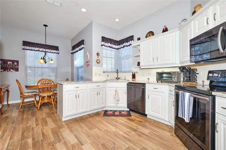 Kitchen with stainless steel appliances, decorative backsplash, open shelves, and white cabinetry