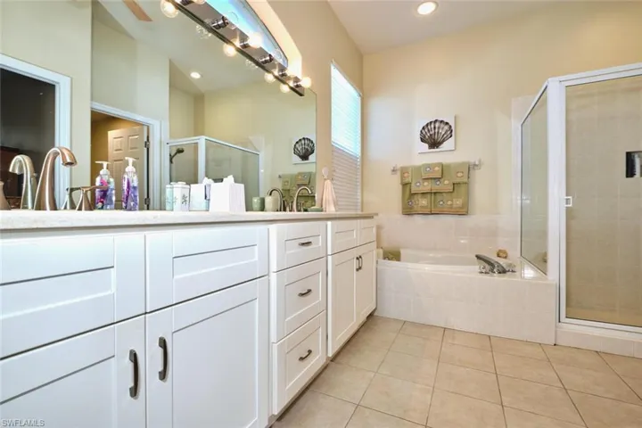 Full bath with a stall shower, vanity, a garden tub, and light tile patterned floors