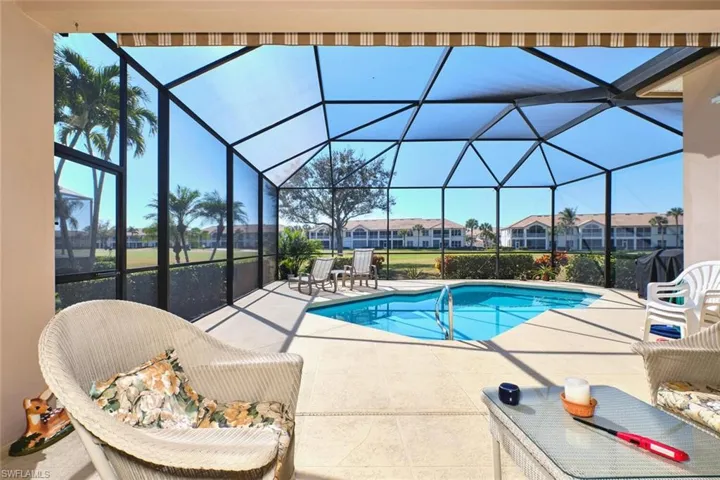 Outdoor pool featuring a sunroom, a patio area, glass enclosure, area for grilling, and a residential view