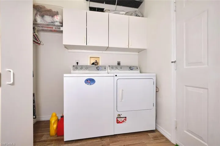 Laundry area featuring cabinet space, washer and clothes dryer, and light wood finished floors